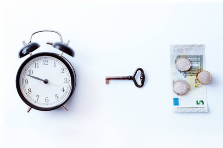 Time is key to money. Time is money. Business concept. Old alarm clock on white background. Cooper key, moneyの写真素材