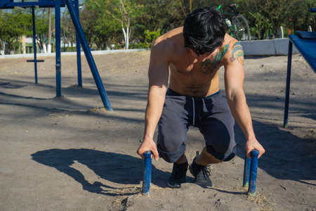 Man doing exercise calisthenics, bent arm straddle planche in park