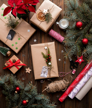 Christmas presents wrapped in kraft paper and decorated with fir branches on wooden backgroundの写真素材