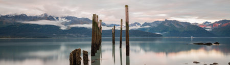 Panoramic view of a serene lake at sunset, with majestic mountains in the background, showcasing the natural beauty of the landscape.の写真素材