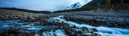 Long exposure of a mountain river flowing over rocks in the mountains at sunsetの写真素材