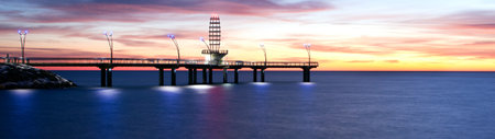 A panoramic view of a pier at sunset in the seaの写真素材