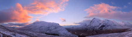 Panoramic view of snow capped mountains at sunset in Scotland.