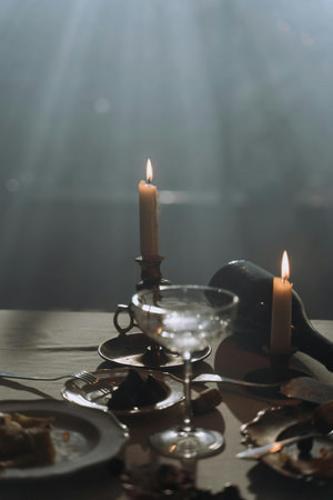 Table setting with candles and wine glasses on wooden table in dark room