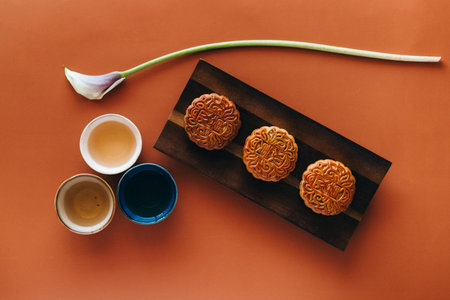 Moon cakes and green tea on brown background. Top view, flat lay