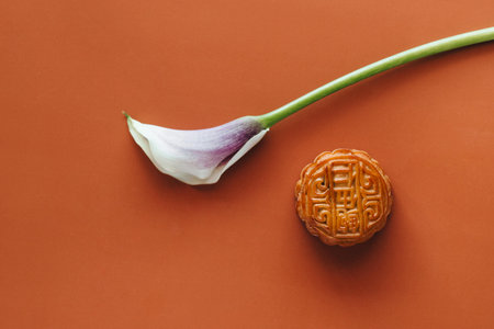 top view of delicious moon cake and white calla flower on orange backgroundの写真素材