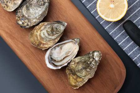 Fresh oysters and lemon on wooden board, top view, closeupの写真素材
