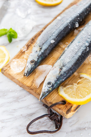 Fresh raw sardines on wooden cutting board with lemon and mint.の写真素材