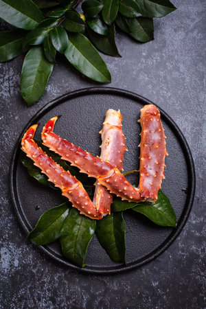 King crab legs on a black plate with green leaves. Top viewの写真素材