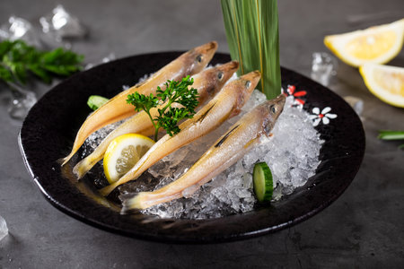 Fresh raw herring on ice with lemon and herbs on dark background