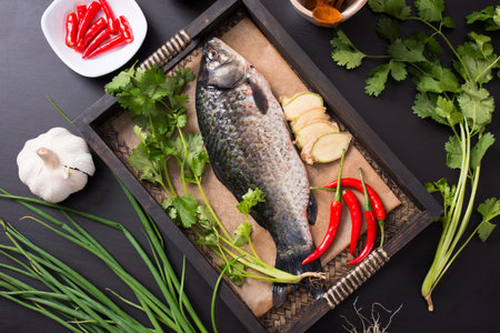 Fresh fish with ingredients for cooking on a black background, top viewの写真素材