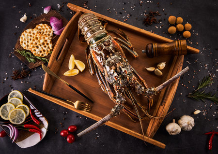 Fresh raw spiny lobster with spices and herbs on black background, top viewの写真素材
