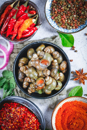 Bowls of fresh snails with chili peppers and spices on stone background, top viewの写真素材