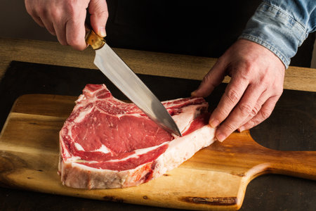 Close up of a man's hands cutting meat on a chopping board
