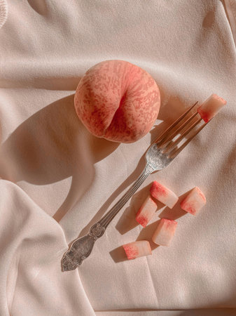 Peach slices and a fork on a background of pink fabric.の写真素材
