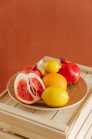 Different types of citrus fruits on a wooden tray on a brown backgroundの写真素材