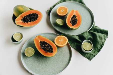 top view of fresh ripe papaya and lime on plates isolated on whiteの写真素材