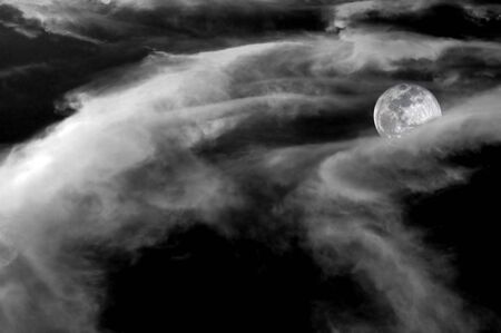 Spooky full moon half covered in contrasting clouds. Black and White. の写真素材