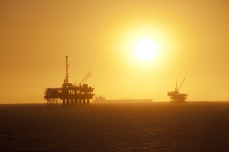 Oil Rigs in the ocean, ship passing by and a beautiful sunset in Huntington Beach, California.の写真素材