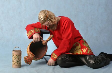 portrait of a man with a red beard and mustache and long blond hair in a red shirt sitting on the floorの写真素材