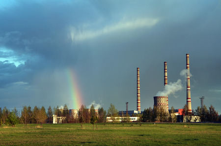 spring landscape rainbow after the rain over the meadow near the power plantの写真素材