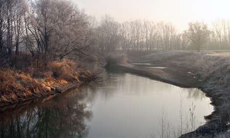 beginning of winter landscape on the river near the shore groves and trees covered with frost at sunsetの写真素材