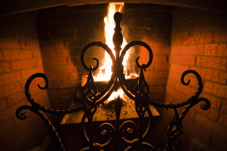 close up of a beautiful wrought-iron grate against the bright flame and a brick wallの写真素材