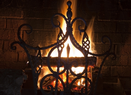 close up of a beautiful wrought-iron grate against the bright flame and a brick wallの写真素材