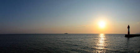 seascape lighthouse in the sea at sunset photographed from a boatの写真素材