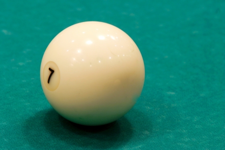 macro one billiard ball ivory number 7 isolated on green backgroundの写真素材
