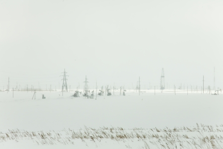 winter landscape power lines in a snowy field near the forestの写真素材