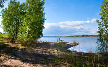 summer landscape beautiful cumulus clouds over a calm river and green trees on the shore on a sunny...