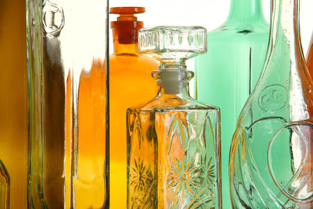 close-up clean transparent colored glass bottles of different shapes on the mirror surface in white light studioの写真素材