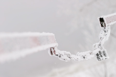 macro chain with a lock on the turnpike in hoarfrost on a background of the river in thick fogの写真素材