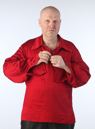 Portrait of a adult white bald man in a red shirt with a cross on his chest on a light background studioの写真素材