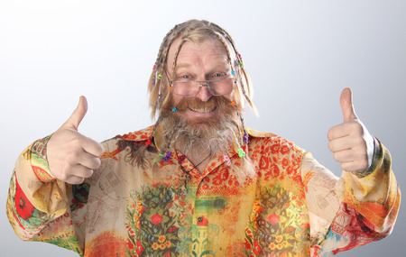 close-up portrait of an adult male with long beard, mustache and hair braided in pigtails gesturing studio on light backgroundの写真素材