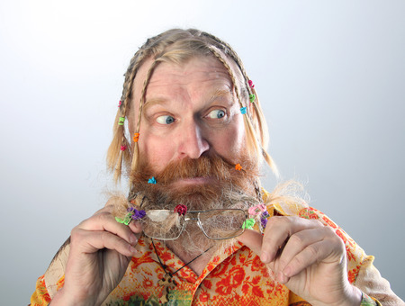 close-up portrait of an adult male with long beard, mustache and hair braided in pigtails gesturing studio on light backgroundの写真素材