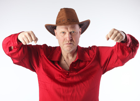 Portrait of a adult white bald man in a red shirt and cowboy hat on white background studioの写真素材