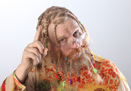 close-up portrait of an adult male with long beard, mustache and hair braided in pigtails gesturing studio on light backgroundの写真素材