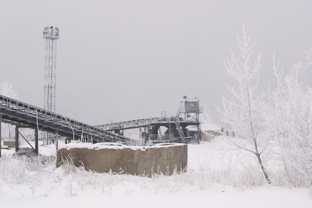 Winter landscape of dense fog on the river ice and trees covered with frost on the shoreの写真素材