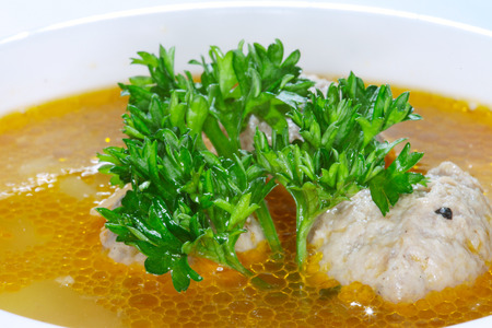 macro delicious rich soup with meatballs garnished a sprig of parsley in a white plateの写真素材