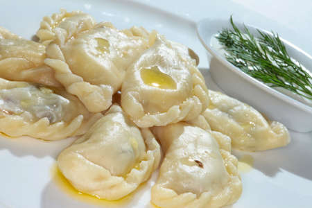 macro boiled dumplings with butter with greenery on white plate