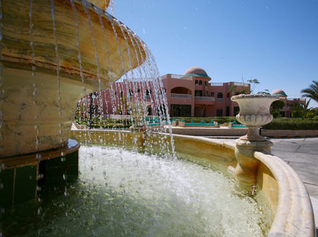 seaside resort hotel building and landscaped grounds with pool and flower beds on a hot sunny dayのeditorial素材