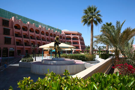 seaside resort hotel building and landscaped grounds with pool and flower beds on a hot sunny dayのeditorial素材