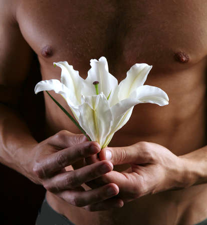 close-up delicate white lily in the hands against the of naked torso, studio dark の写真素材
