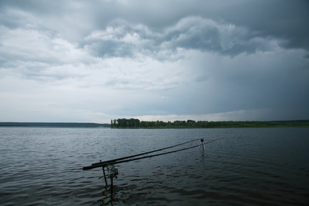 summer landscape storm clouds over the river and spinning on a stand near the shoreの写真素材