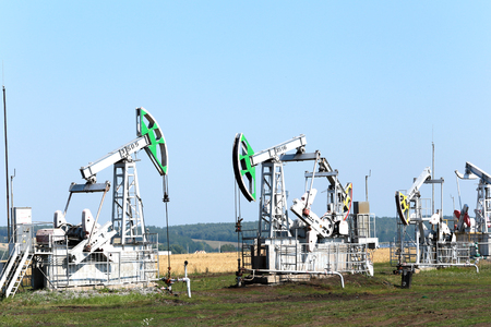 summer landscape oil pumps in the grain fields on the blue sky on a sunny dayのeditorial素材