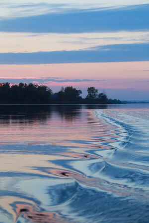 close-up amazing wavy trace of the boat on the river at sunset