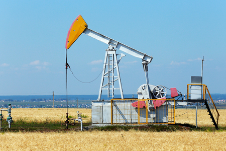 summer landscape oil pumps in the grain fields on the background of the blue sky on a sunny dayの写真素材