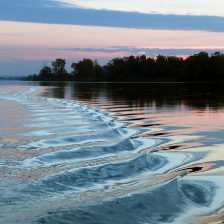 close-up amazing wavy trace of the boat on the river at sunsetの写真素材